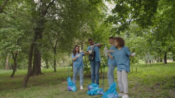 Equipe de voluntários bebendo água, desfrutando de limpeza acabada ao ar livre — Vídeo de Stock