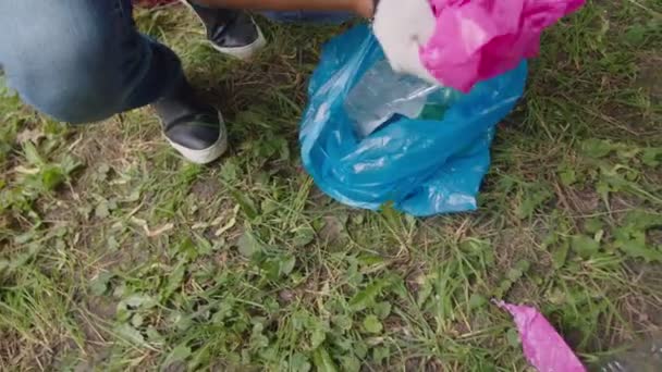 Detailní záběr na prostředí uvědomující muž zvedání plastu do pytle na odpadky — Stock video