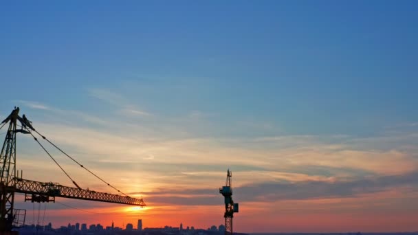 Vue aérienne des grues de construction, paysage urbain en arrière-plan au coucher du soleil — Video