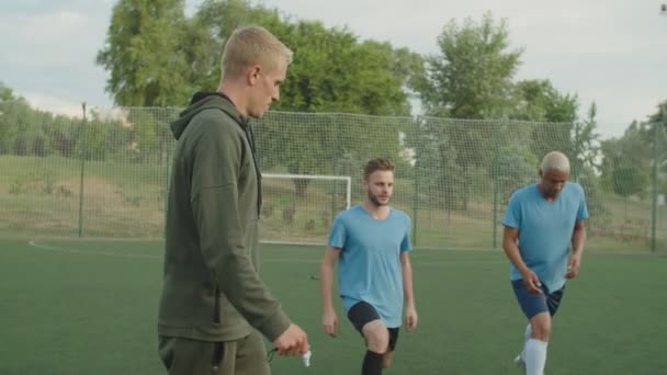 Coach controleren uitvoeren van stretching oefening door het team buiten — Stockvideo