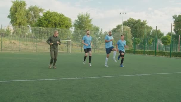 Jugadores de fútbol realizando ejercicio de rodilla alta corriendo al aire libre al amanecer — Vídeos de Stock