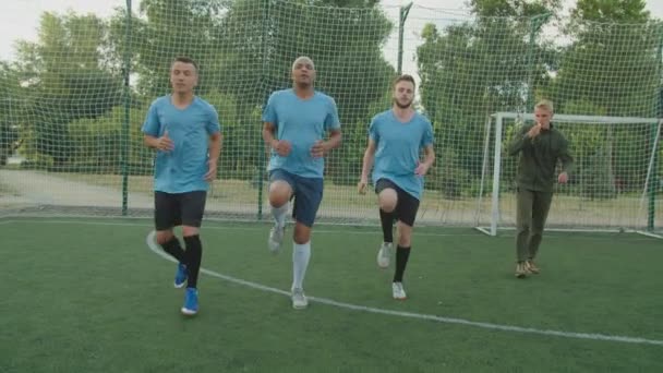 Framifrån på fotbollsspelare som utför hög knä kör utomhus — Stockvideo