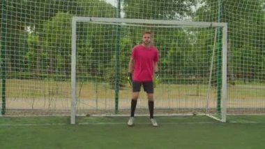 Futbol kalecisi sahada futbolu savunmak için antrenman yapıyor.