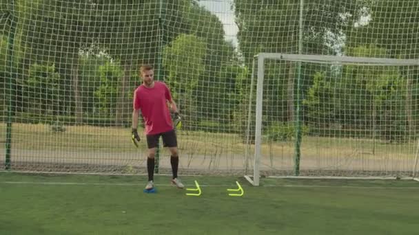 Чоловічий футбольний воротар, що виконує складне тренування, ловить м'яч на відкритому повітрі — стокове відео