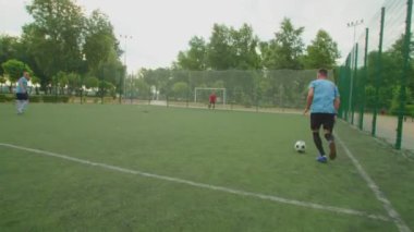 Futbolcu top sürüyor, gol atıyor. Şafakta futbol sahasında.