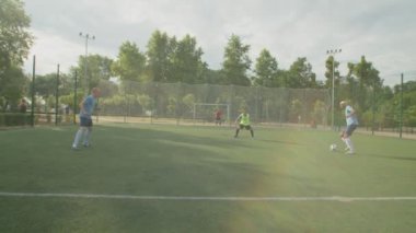 Spor giyimli bir grup futbolcu şafakta futbol sahasında oynuyor.