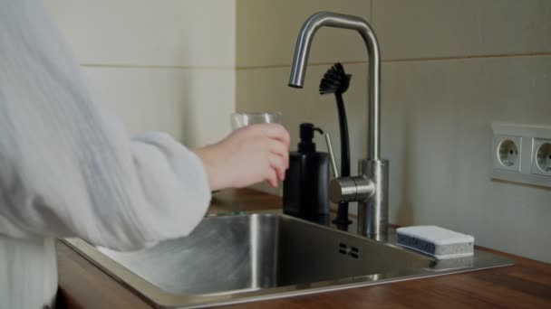 Woman pouring fresh filtered water into glass from faucet indoors — Stock Video
