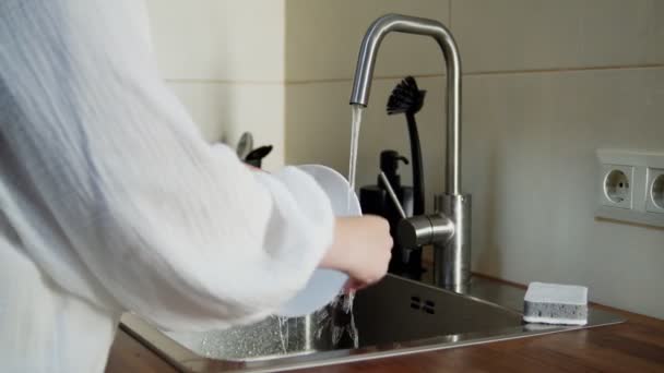 Evdeki mutfak lavabosunda bulaşıkları yıkayan tanınmayan bir kadın. — Stok video