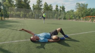 Futbol takımındaki yaralı futbolcu faulden sonra futbol sahasında yatıyor