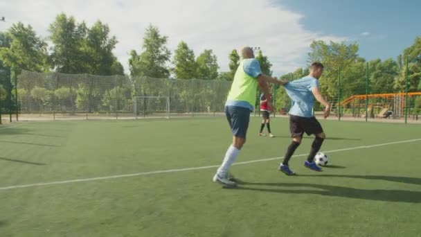 Vista lateral del defensor de fútbol tirando de la camisa delantero en el campo de fútbol — Vídeos de Stock