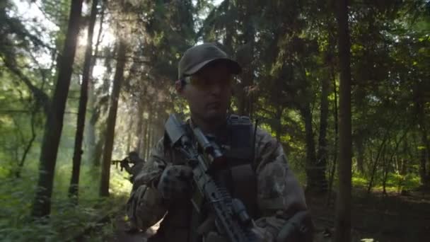 Primer plano del soldado con rifle mientras el grupo militar se mueve detrás — Vídeos de Stock