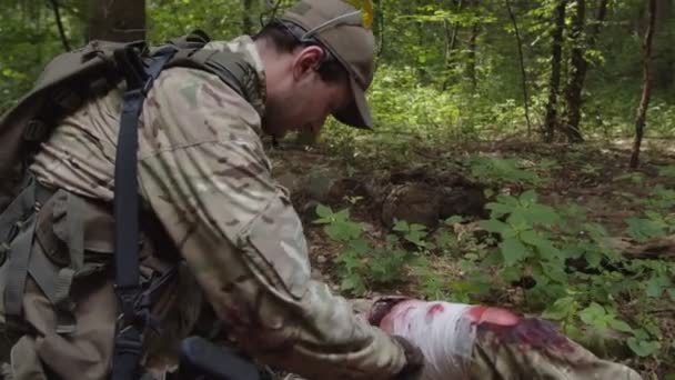 Бойовий медик надає екстрене лікування пораненому солдату на відкритому повітрі — стокове відео