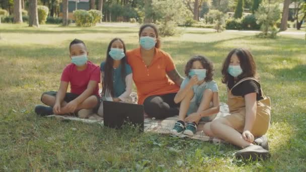 Los escolares y el maestro en la protección médica mascarillas al aire libre — Vídeos de Stock