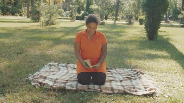 Uma mulher a ler livros. Crianças correndo para a professora, abraçando-a ao ar livre — Vídeo de Stock