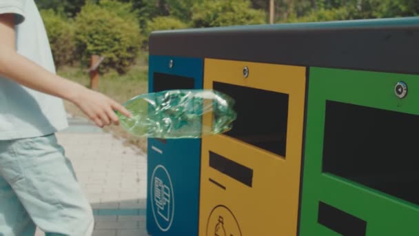 Chico rizado lanzando botella de plástico vacía en el cubo de basura de reciclaje al aire libre — Vídeos de Stock