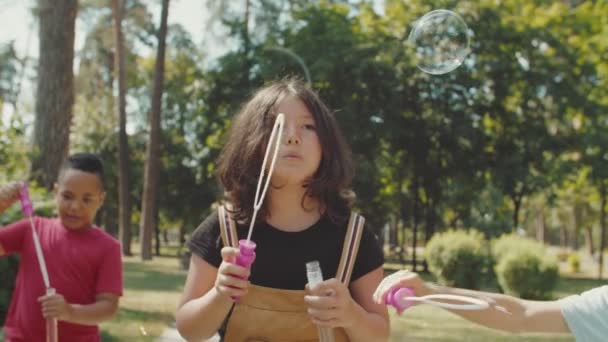 Elementary age kids blowing bubbles while spending leisure time in park — Stock Video