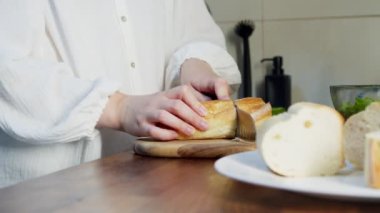 Mutfak bıçağıyla ekmek doğrayan bir kadın.