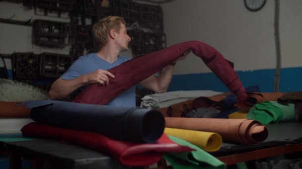 貯蔵室に棚に本物の革のロールを積み重ねるジャーニーマン — ストック動画