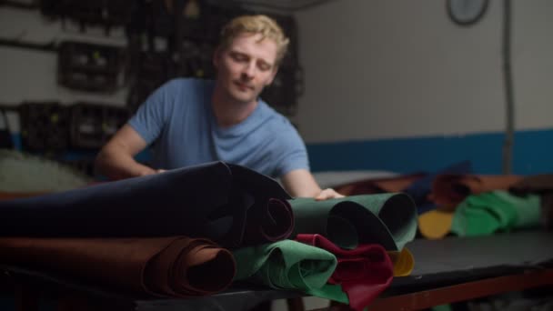 Artigiano che sceglie materiale in pelle da rotoli multicolori al chiuso — Video Stock