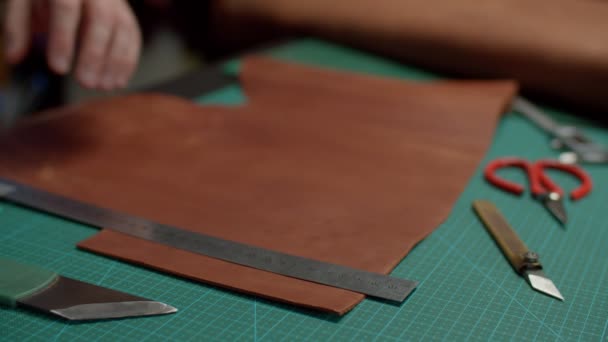 Close-up of leather sheet cutting by craftsman, using knife indoors — Stock Video