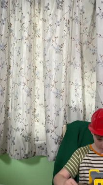 İlkokul çağındaki neşeli genç bir çocuk kapalı bir masada otururken oyuncaklarla oynuyor. Enerji ve hayal gücüyle dolu, rahat, güvenli ve yaratıcı bir ortamda eğleniyor.. 