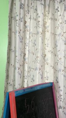 Okul çağındaki çocuk evde ders çalışıyor, ödevlerini özveriyle yapmaya odaklanmış. Öğrenmeyi destekleyen sakin bir ortamda okuma ve sayma, bilgi ve beceriler geliştirme pratiği yapıyor.. 