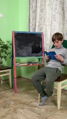 Okul çağındaki çocuk evde ders çalışıyor, ödevlerini özveriyle yapmaya odaklanmış. Öğrenmeyi destekleyen sakin bir ortamda okuma ve sayma, bilgi ve beceriler geliştirme pratiği yapıyor.. 