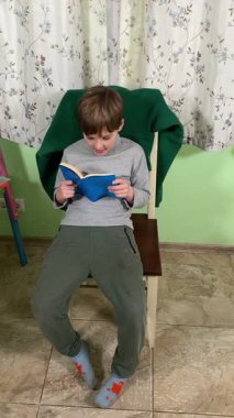 Okul çağındaki çocuk evde ders çalışıyor, ödevlerini özveriyle yapmaya odaklanmış. Öğrenmeyi destekleyen sakin bir ortamda okuma ve sayma, bilgi ve beceriler geliştirme pratiği yapıyor.. 