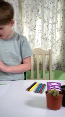 Evde kalemlerle resim çizen sevimli bir okul çocuğu. Yaratıcı bir işle uğraşıyor. Hobisine odaklanmış, evde boş vakit geçirirken hayal gücü ve sanatsal beceriler geliştiriyor.. 