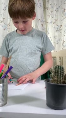 Evde kalemlerle resim çizen sevimli bir okul çocuğu. Yaratıcı bir işle uğraşıyor. Hobisine odaklanmış, evde boş vakit geçirirken hayal gücü ve sanatsal beceriler geliştiriyor.. 