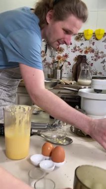 Önlüklü genç baba ve küçük kızı mutfakta birlikte yemek pişiriyorlar. Aile tatillerini paylaşırlar, yemek hazırlama ve sıcak bir yuva ortamında eğlenceli etkileşimlerle eğlenirler.