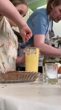 Önlüklü genç baba ve küçük kızı mutfakta birlikte yemek pişiriyorlar. Aile tatillerini paylaşırlar, yemek hazırlama ve sıcak bir yuva ortamında eğlenceli etkileşimlerle eğlenirler.