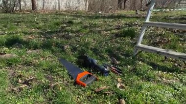 Genç bir adam güneşli bir bahar gününde ağaçları buduyor ve el aletleriyle bahçeyle ilgileniyor. Mevsimlik bahçe işleri, dalları budamak, bahçe bakımı ve parlak güneş ışığında yeni bir başlangıç konsepti.