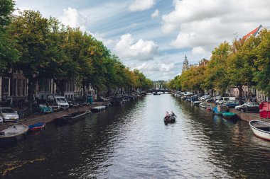 Karmaşık kanalları olan Amsterdam 'ın yüzü, mavi gökyüzü, beyaz bulutlar, yeşil ağaçlar