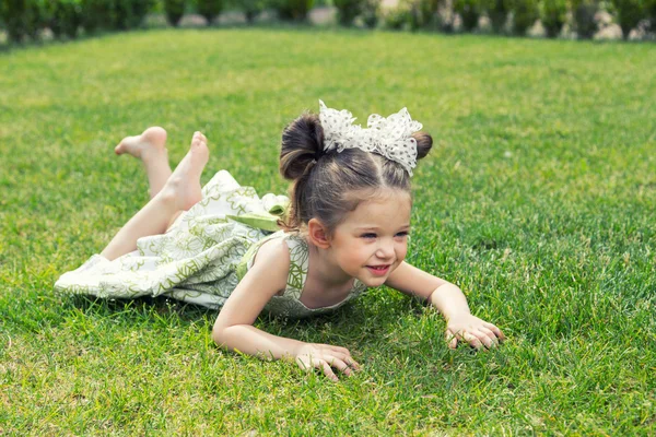 Beautiful little girl lying on the grass — Stock Photo, Image