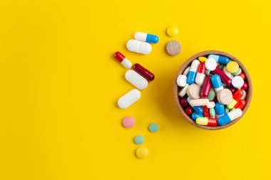 Ahşap bir kapta çeşitli ilaç hapları, haplar ve kapsüller var. Tıbbi konsept. Çeşitli hastalık tehdidi kavramı. Üst Manzara. Metin için boşluk.