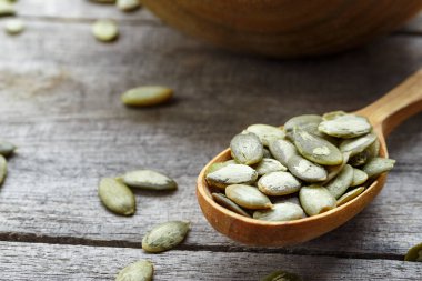 Tahta bir arka planda tahta kaşıkta kabak çekirdeği çekirdekleri.