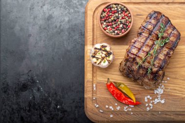 Ahşap kesme tahtasında servis edilen baharatlı bir parça pişmiş biftek.