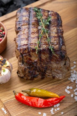 Ahşap kesme tahtasında servis edilen baharatlı bir parça pişmiş biftek.