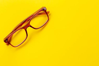 Sarı arka planda kırmızı çerçeveli moda gözlükler. Sağlık konsepti. Gözleri inceleyen tıbbi alan..