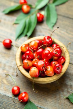 Tahta bir masada, yaprakları olan taze kirazlar..