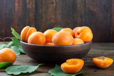 Masanın üzerindeki kil kasede leziz olgun kayısılar. Sağlıklı meyve.