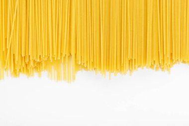 Beyaz arka planda sarı, uzun bir spagetti. İtalyan yemeği ve menü konsepti. Mesaj için yer var. Üst görünüm.