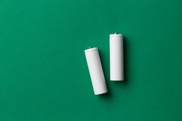 Rechargeable AAA batteries in white on a green background. Place for text. Green energy concept.