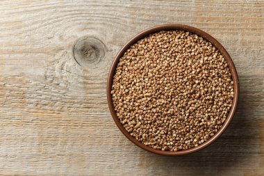 Ahşap bir arka planda kil bir maskede çiğ karabuğday. Mesaj için yer var. Üst görünüm.