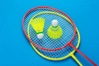 Mavi arka planda iki tane badminton raketi. Aktif eğlence ve spor konsepti. Metin için boşluk. 