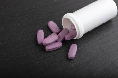 Pembe haplar siyah arka planda beyaz bir tüpten yayılmış. Sağlık hizmeti konsepti. Mesaj için yer var. Üst görünüm.