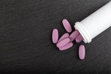 Pembe haplar siyah arka planda beyaz bir tüpten yayılmış. Sağlık hizmeti konsepti. Mesaj için yer var. Üst görünüm.