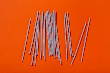 Meyve suyu için renkli borular ve turuncu arka planda kokteyller. Mesaj için yer var. Üst görünüm.