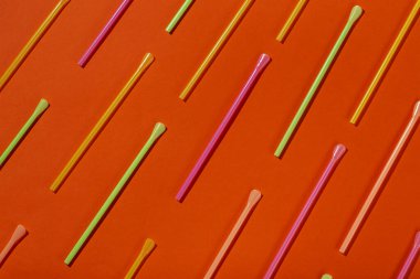 Portakal suyu için renkli tüpler ve turuncu arka planda kokteyller.